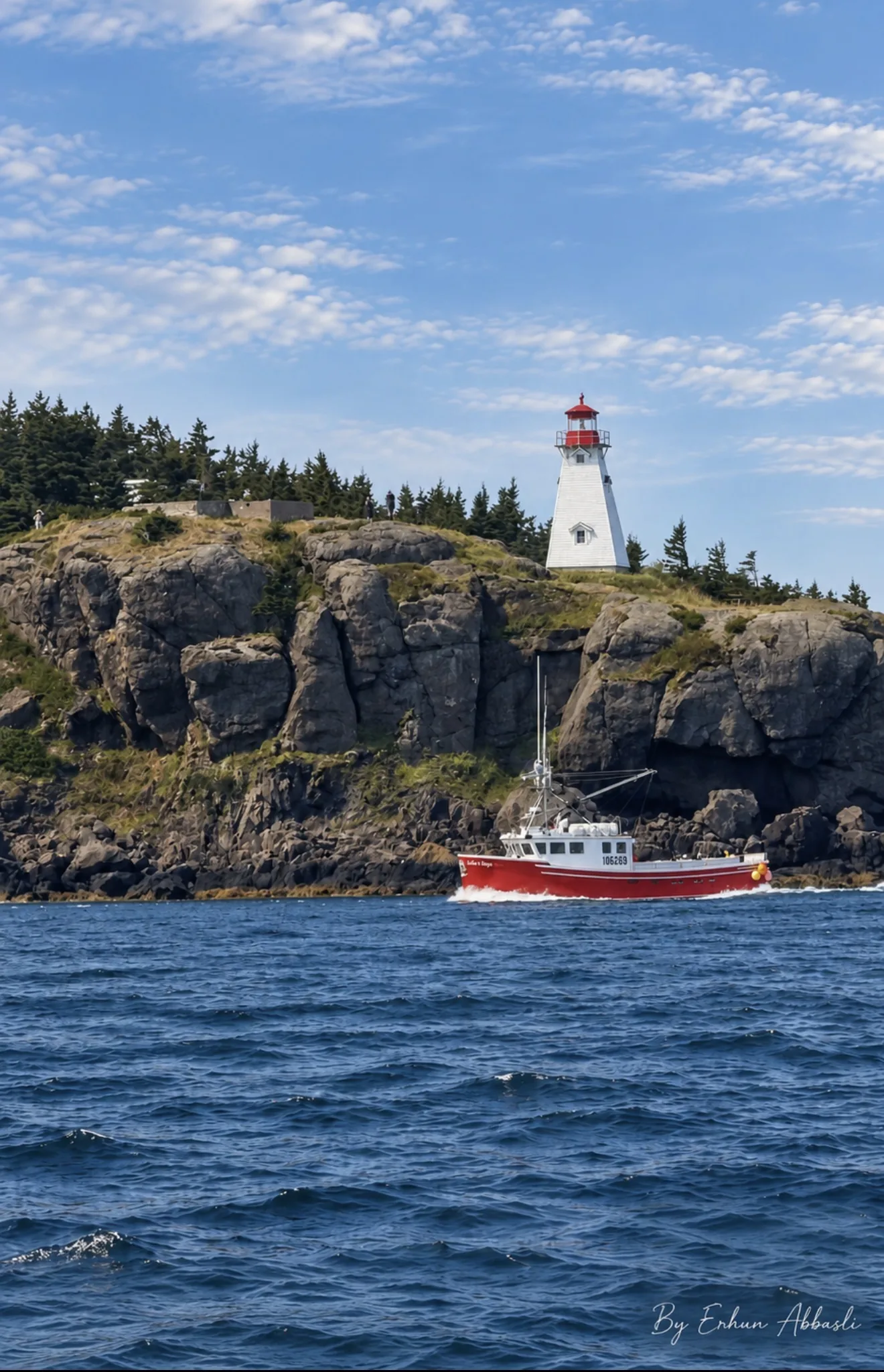 Lighthouse on the cliffs at Digby Neck with a red fishing boat passing below, Nova Scotia